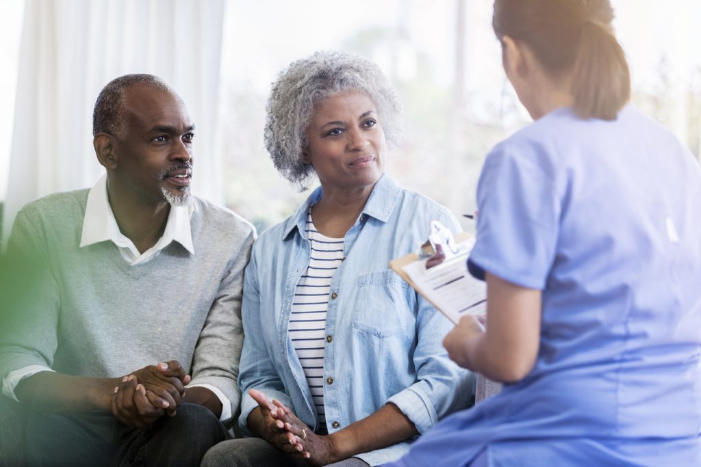 Photo of a couple sitting in a doctor's appointment looking relieved