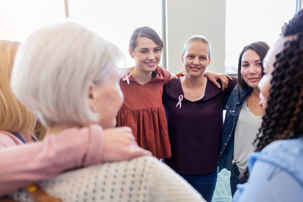 Members of a breast cancer support group stand showing support 