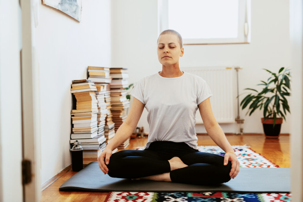 Person living with cancer meditating on a yoga mat