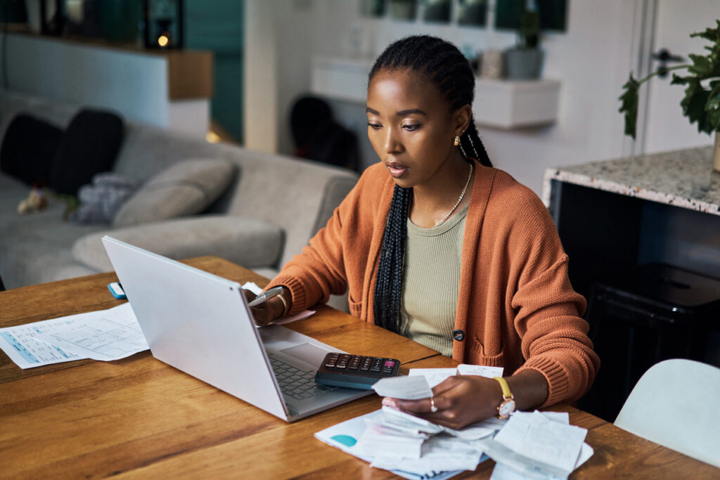Caregiver paying medical bills on her computer while sitting at a wood table