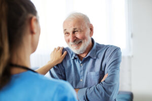 Photograph of an aging man talking to a health care professional about palliative care