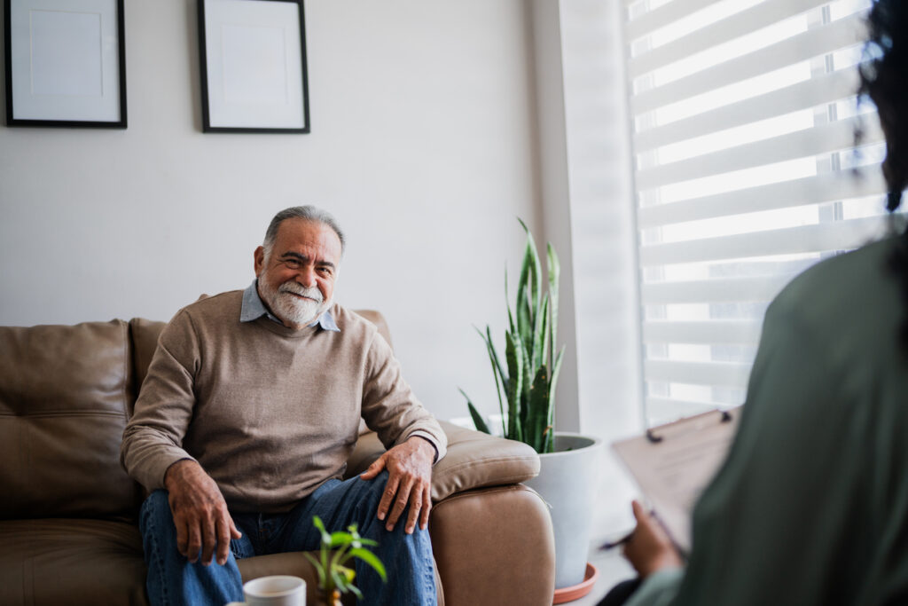 Male patient or caregiver sits on couch and talks to a chaplain